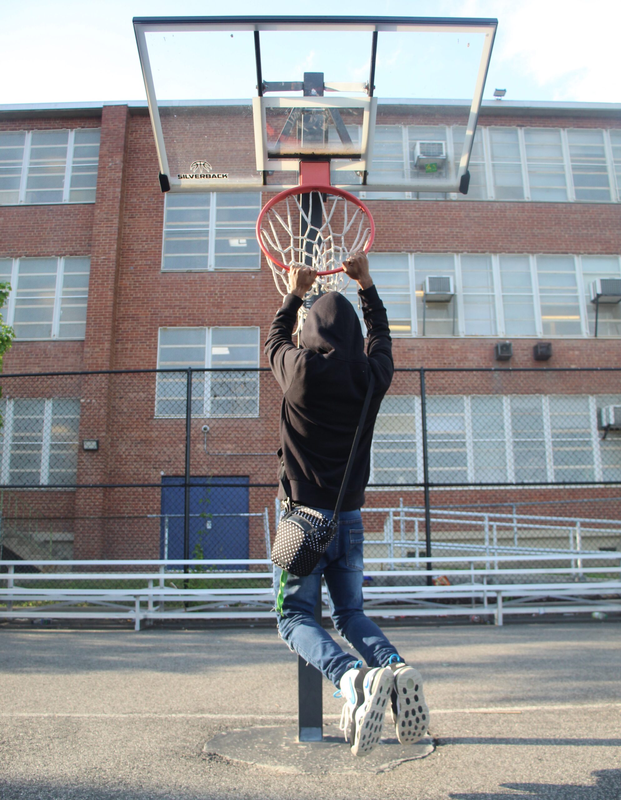 image of a boy on the basketball court handing from a basket ball rim.