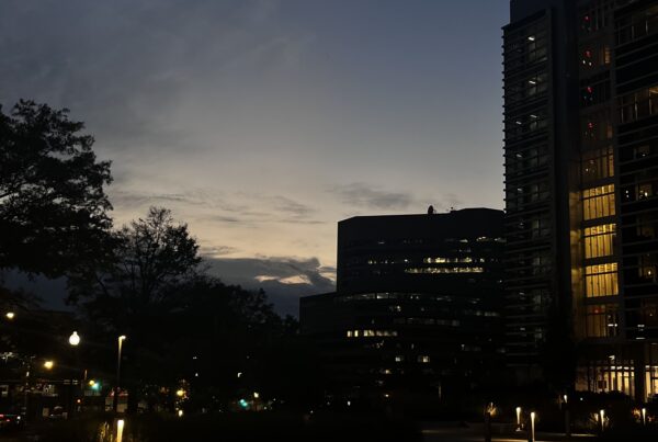 Image of the city buildings at night with glimpses of illumination from the street lights and apartment buildings.